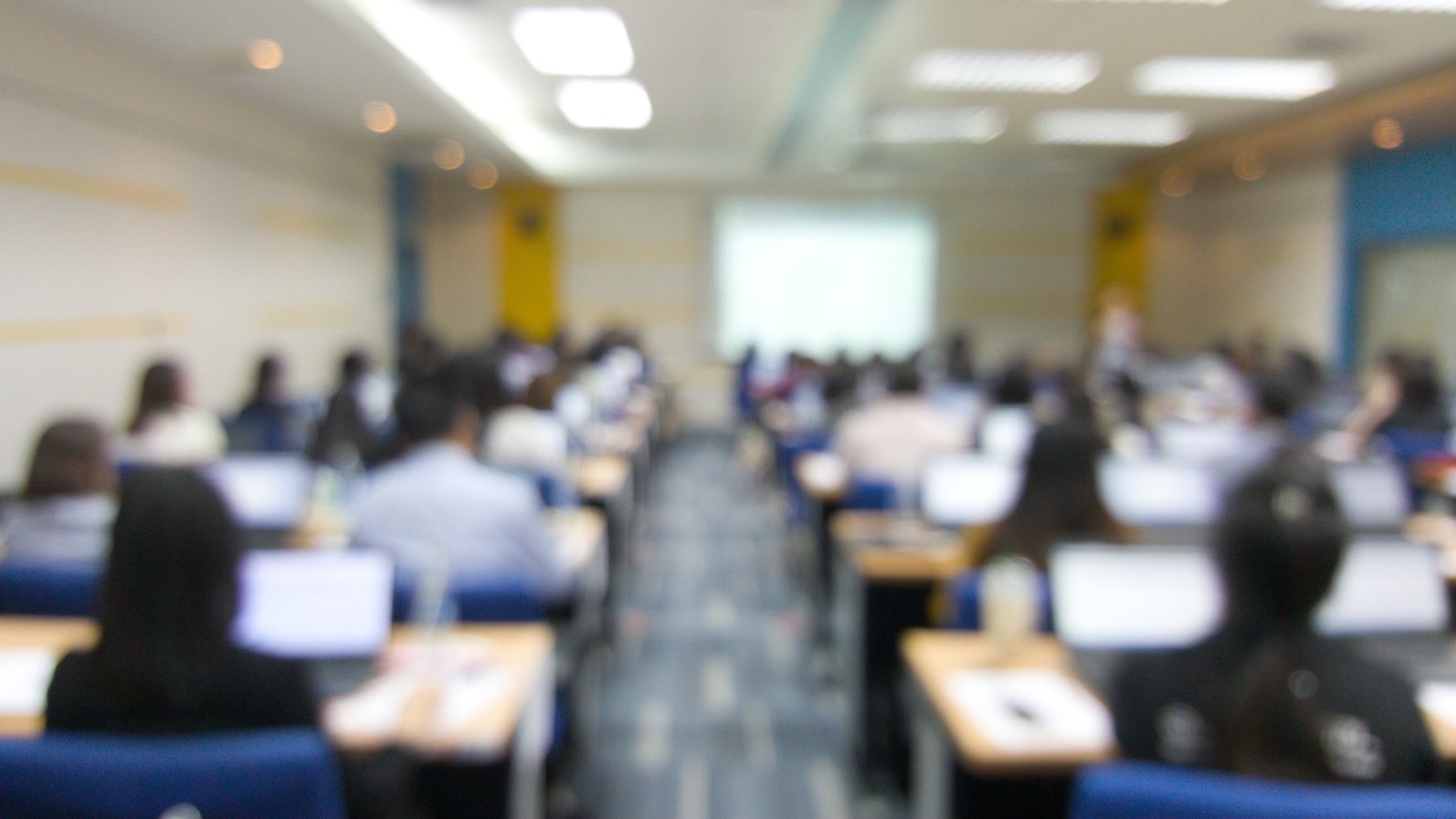 Blur image of many people are training in the big training room with computer.